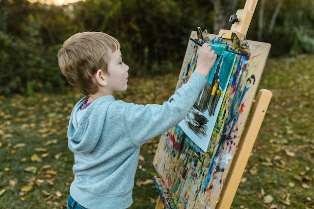 jongen schildert buiten op het gras een schilderij