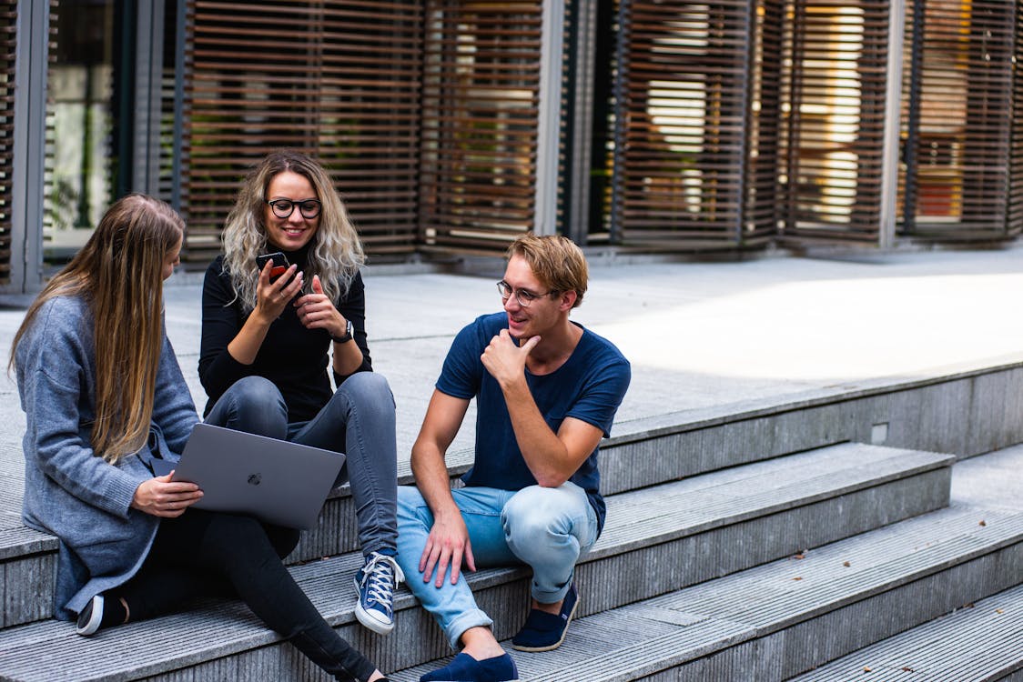 Drie personen zittend op de trap met elkaar praten